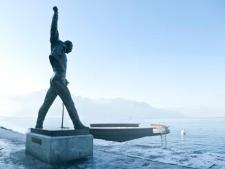 gray metal statue of man raising hand near dock