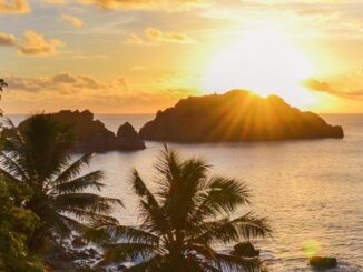 silhouette of rock formation on sea during sunset
