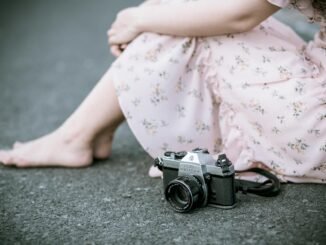 sitting woman wearing pink floral dress beside gray camera