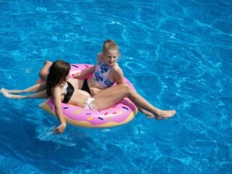 two girls sitting on pink doughnut pool float