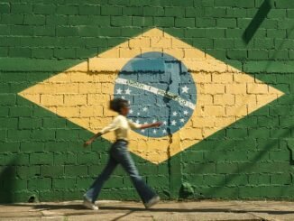 girl walking on street with brazilian flag on wall