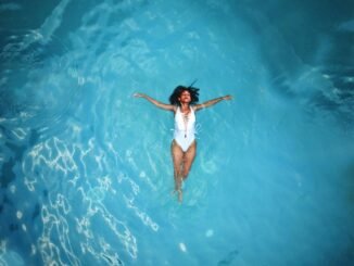 woman in white monokini swimming on body of water