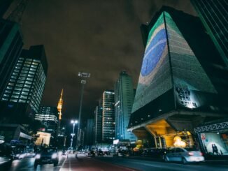 cars traveling on road between buildings during nighttime