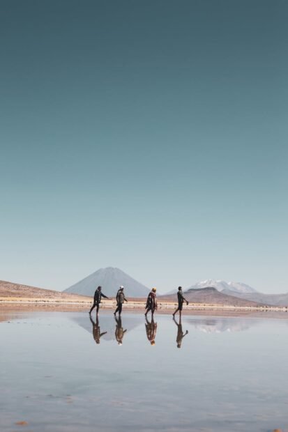 four people walking across a lake in the desert