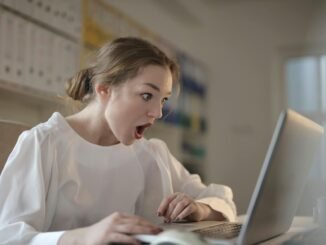 woman in white long sleeve shirt using silver laptop computer