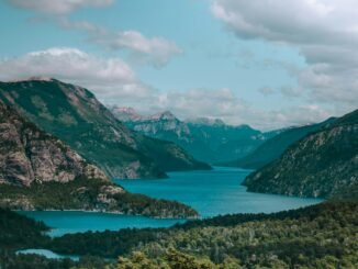 green mountains near lake under white clouds and blue sky