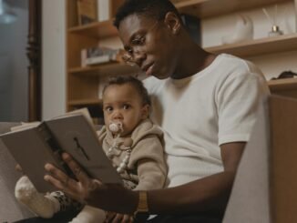 a man reading book to a baby with pacifier