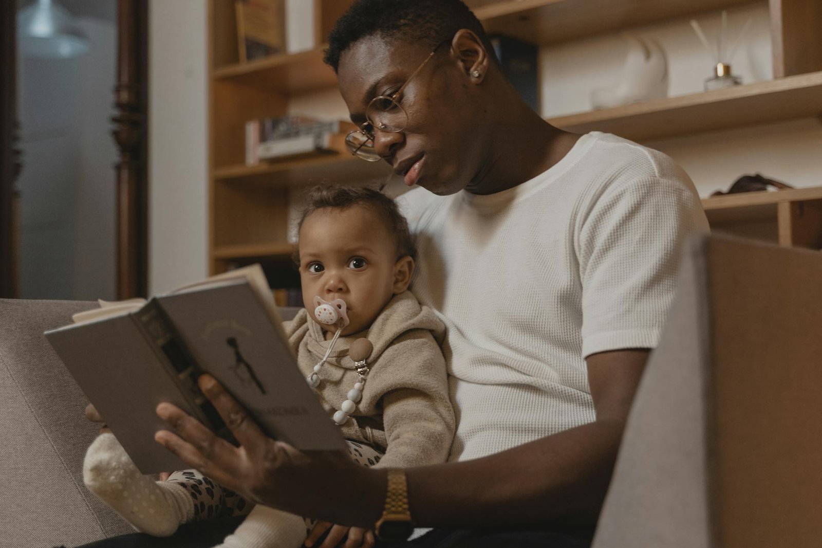 a man reading book to a baby with pacifier